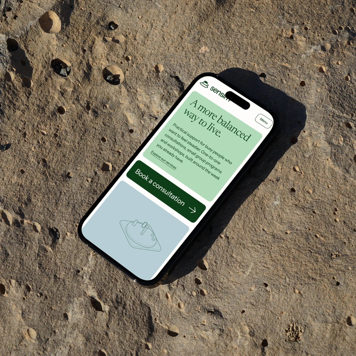 Sensim website: Phone resting on a sandy rock, showing the Sensim mobile home page