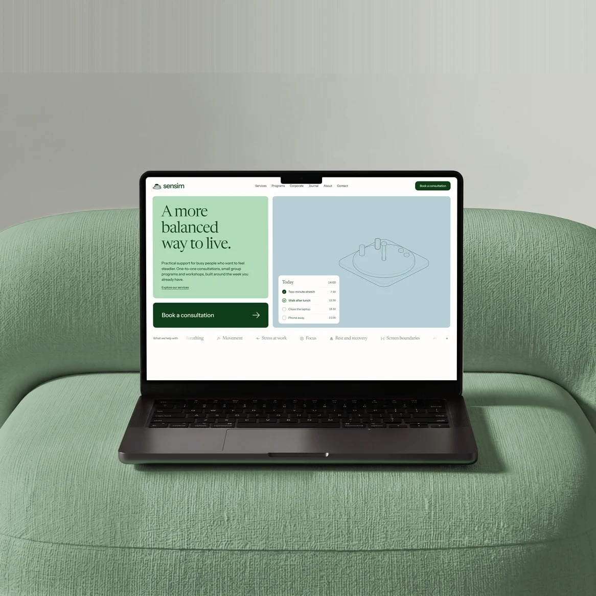 Sensim website: Laptop on a sage bouclé armchair showing the Sensim home page: 'A more balanced way to live' and a book-a-consultation button