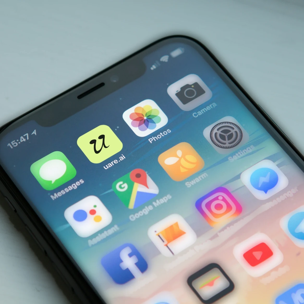 Uareai website: Close-up photo of a phone home screen with the uare.ai app icon among everyday apps