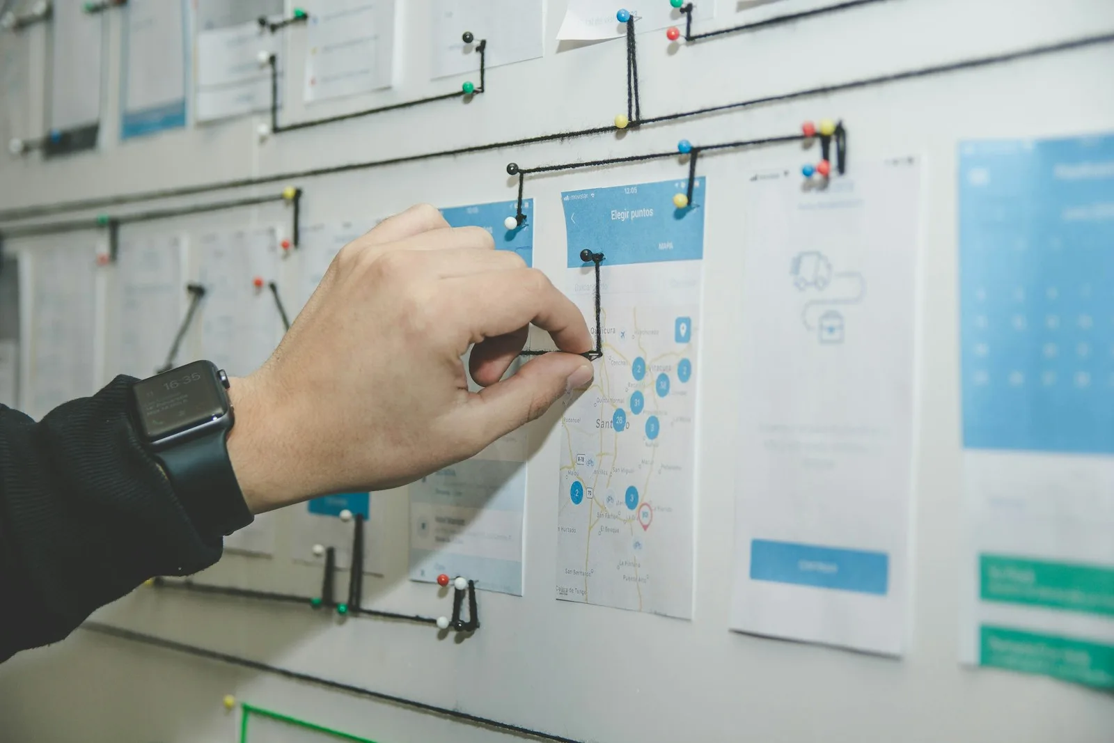A hand pinning website page sketches to a wall, connected like a sitemap