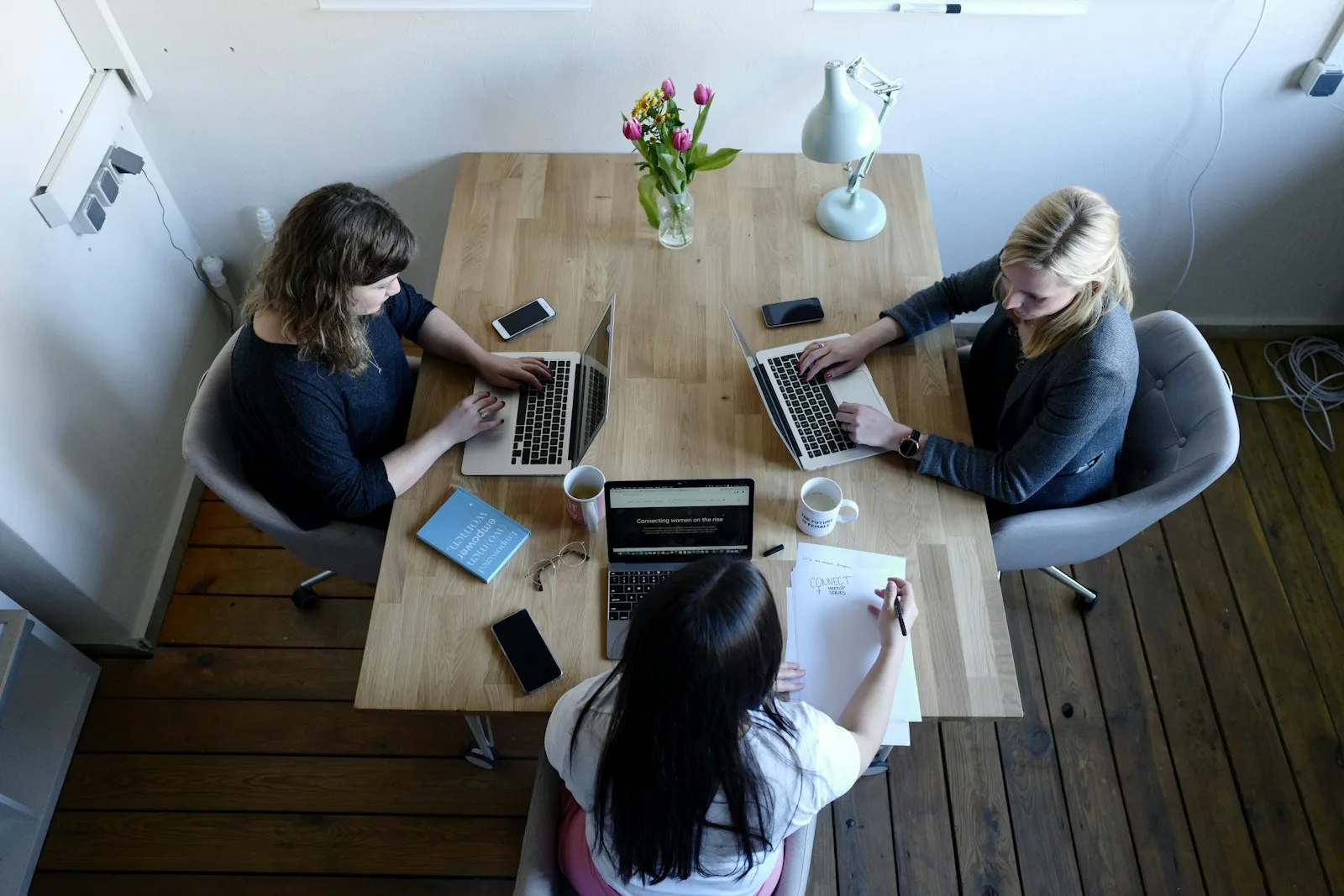Three people working on laptops around a shared table